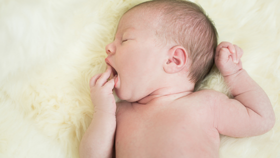 How often to feed a newborn - baby brings hand to face toward mouth
